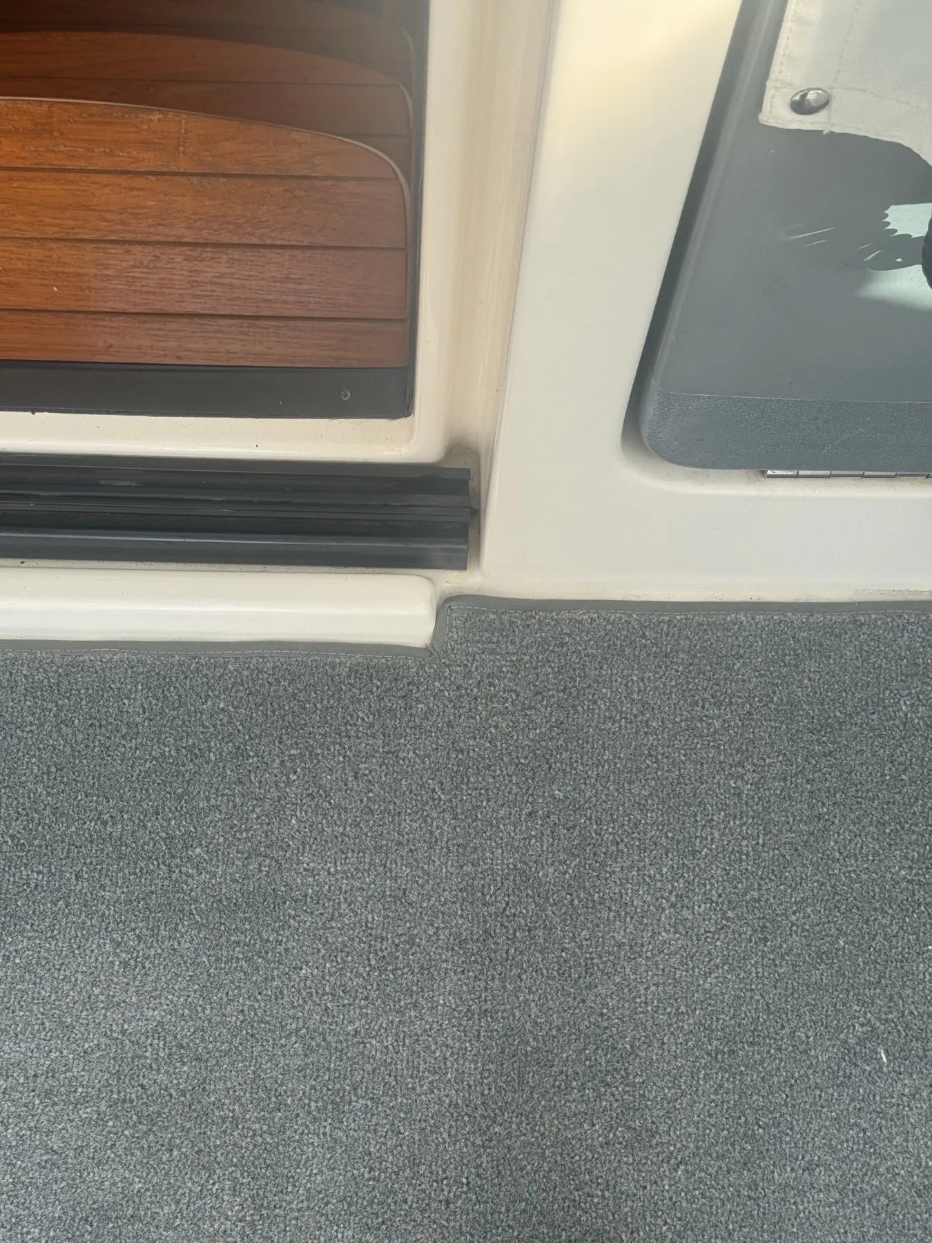 Close detail of a bound carpet edge meeting the cabin door threshold
