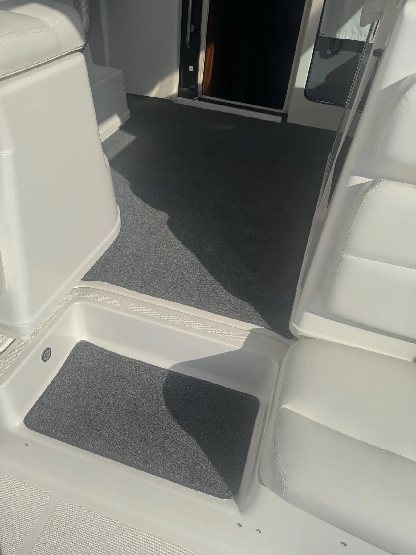 Bonded charcoal marine carpet running through a cockpit, with a bound insert set into the moulded step