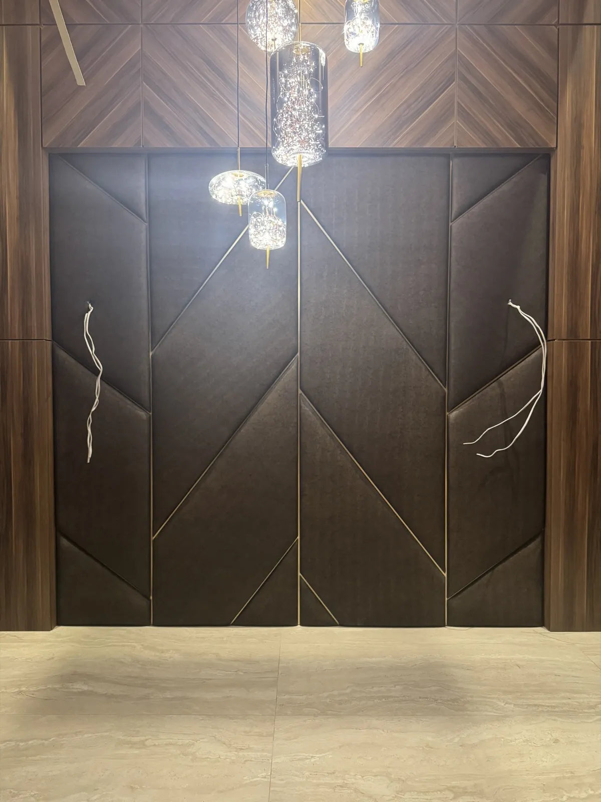 The same opening finished in dark suede chevron upholstered panels with brass inlay lines, under a walnut header