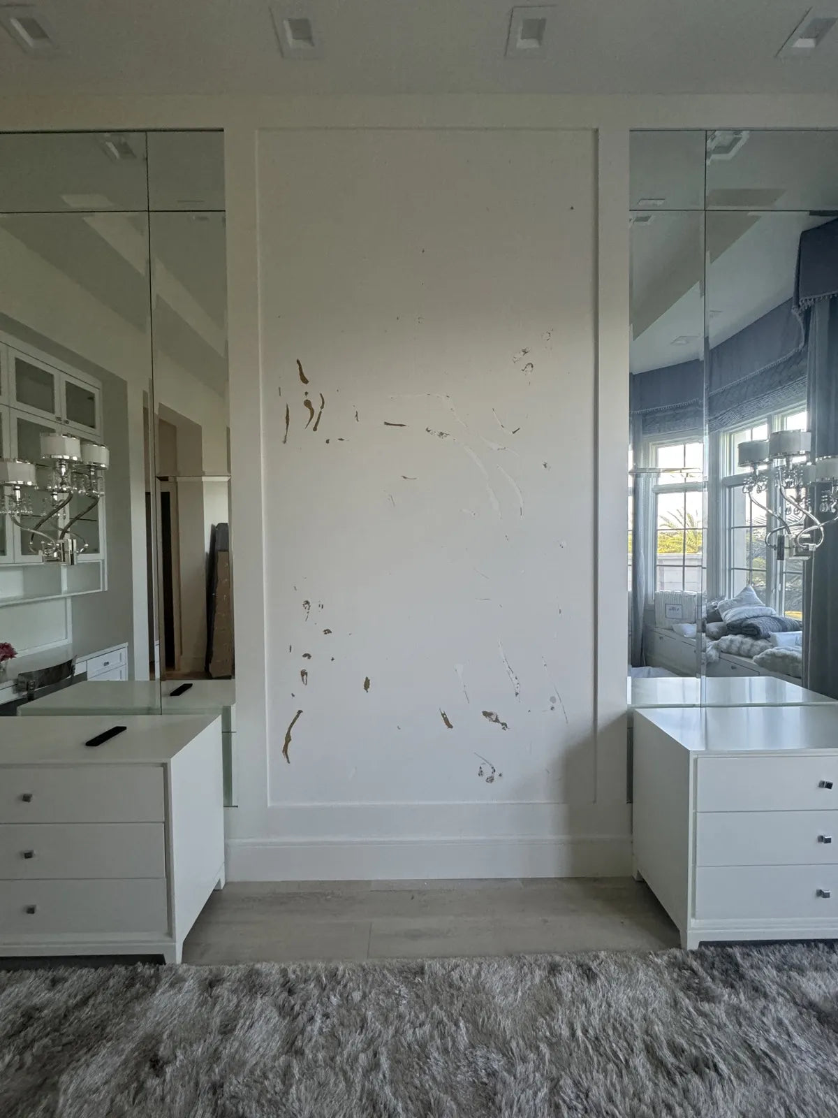 A bare painted wall between two mirrored panels, with torn drywall paper where the previous covering was pulled off