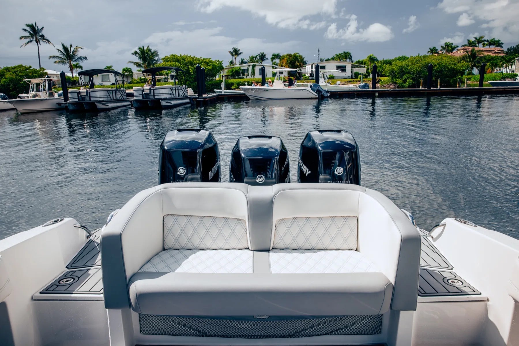 White diamond-stitch aft bench and cushion, looking astern over triple outboards