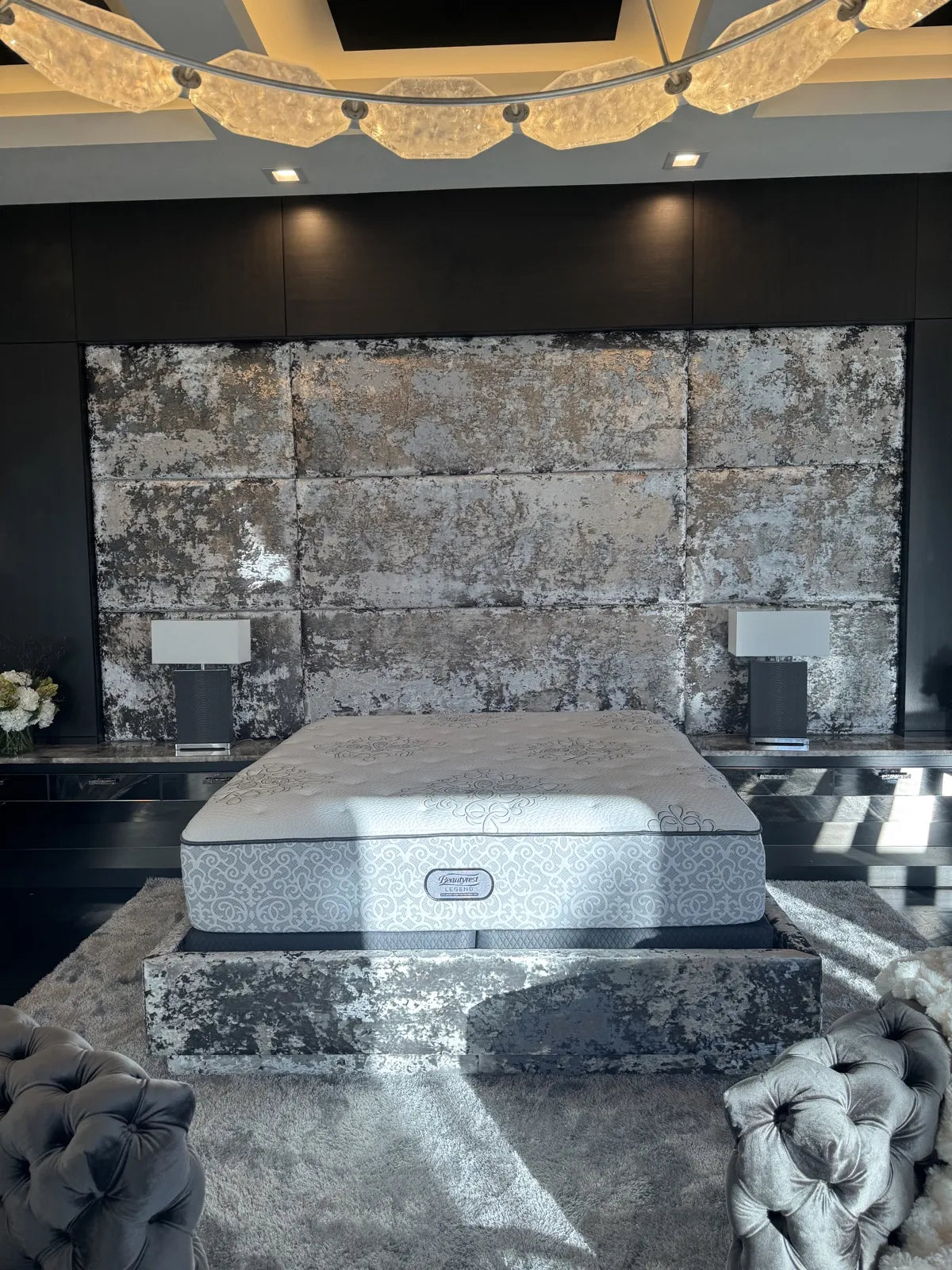 Full-height upholstered headboard wall in a distressed silver and charcoal fabric, set into dark joinery