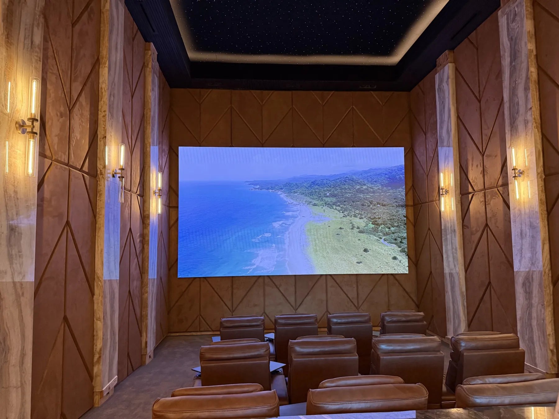 Home theater with chevron-patterned upholstered wall panels running floor to ceiling on three walls, stone pilasters between them and a star ceiling