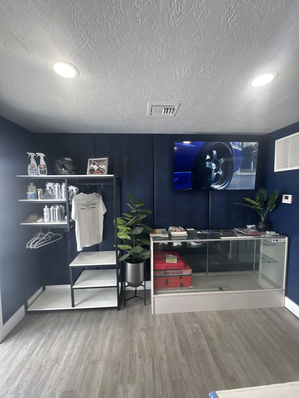 Upholstered navy crocodile-embossed wall panels behind a wall-mounted television in the Rivers Refined showroom